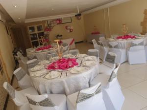 a room with white tables and chairs with pink flowers at Ecotel OR Tambo Airport in Kempton Park +62 photos