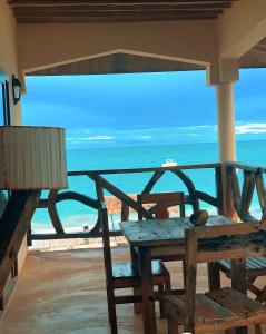 - une table et une chaise en bois sur une terrasse couverte donnant sur l'océan dans l'établissement White Sands, à Paje