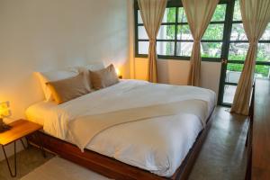 a bedroom with a bed with white sheets and windows at Big Tree Boutique Hotel in Ko Tao