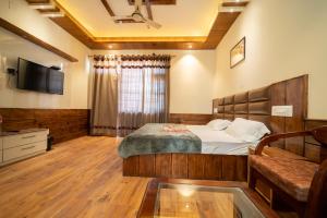 ShamshiMathan View Homestay - 3min Drive to Kullu-Manali Airport的卧室里有一张床和一台电视机