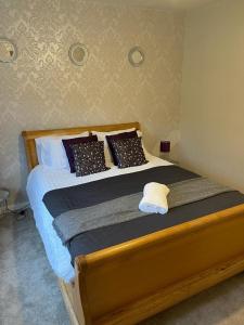 una camera con letto in legno e cuscini di Silver Stag Properties,Comfy House in Coalville a Hugglescote