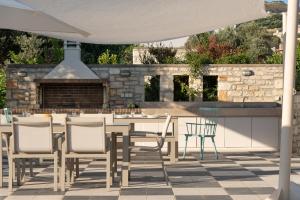 a patio with a table and chairs and an outdoor kitchen at Eco Villa, a perfect escape close to the beach, By ThinkVilla in Maroulás