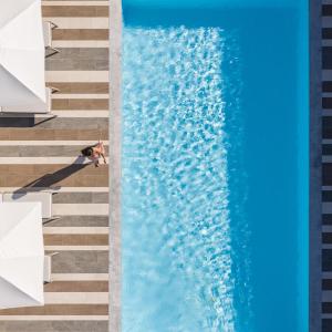 an overhead view of a person sitting on the edge of a swimming pool at Eco Villa, a perfect escape close to the beach, By ThinkVilla in Maroulás