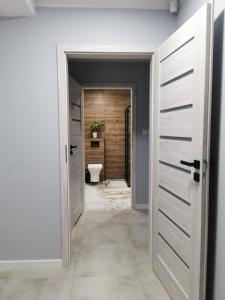 a bathroom with a toilet and a corridor with doors at Na Jedwabnej in Lubawka