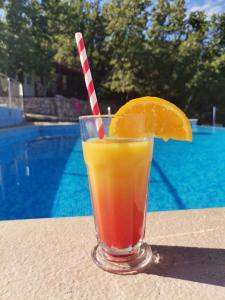 a glass of orange juice sitting on a table next to a pool at Krk Mobile Homes in Klimno