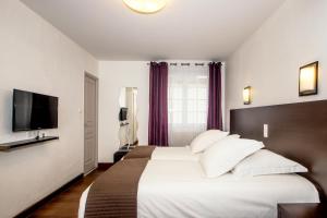 a hotel room with a large bed and a flat screen tv at The Originals Boutique, Hôtel La Baie de Morlaix in Carantec