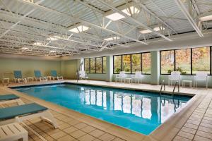 uma piscina num quarto de hotel com cadeiras, mesas e janelas em Wingate by Wyndham Bridgeport Clarksburg em Bridgeport