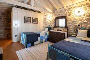 a bedroom with two beds and a stone wall at Traços D'Outrora in Vale de Cambra +43 photos