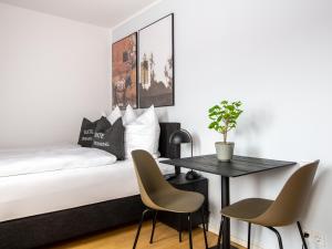 een slaapkamer met een bed met een tafel en stoelen bij limehome Passau Bahnhofstraße in Passau