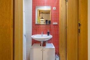 a bathroom with a sink and a red tiled wall at Bocage Loft (Setúbal downtown) in Setúbal