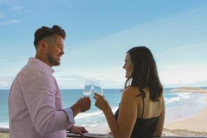 a man and a woman holding glasses of wine at Fistral Beach Hotel and Spa - Adults Only in Newquay