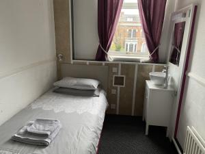 een kleine kamer met een bed en een wastafel bij Bentleys in Newcastle upon Tyne