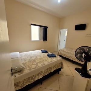 a bedroom with two beds and a fan at Pousada Dona Helena in Morungaba