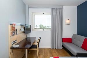 Habitación con sofá, escritorio y ventana. en Holiday Inn Express Barcelona - Montmeló, an IHG Hotel en Granollers