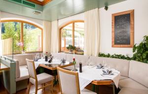 un restaurante con mesas y sillas blancas y ventanas en Gästehaus Zugspitzblick, en Berwang