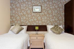 two twin beds in a room with wallpaper at The Black Horse in Swaffham Bulbeck