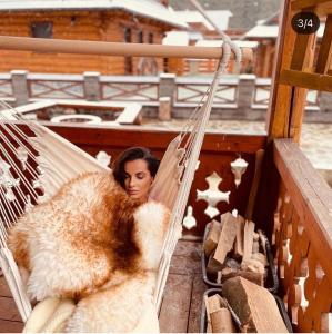 a woman sitting in a hammock with a fur blanket at Wellness drevenica Hájenka Zázrivá in Zázrivá