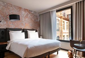 a bedroom with a large bed and a window at Hôtel LÉONOR the place to live in Strasbourg