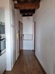 a kitchen with white walls and a wooden floor at Tuscany boutique apartment in Manciano +4 photos