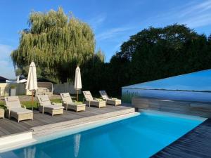 a swimming pool with lounge chairs and umbrellas next to at Fleesensee Resort & Spa in Göhren-Lebbin