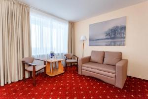 Habitación de hotel con silla, sofá y mesa en AMAKS Valdaiskie Zori, en Valday