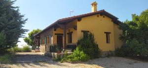 a small yellow house with a cross on the roof at Pago de Yuste - Casa Rural Apartamentos in Cuacos de Yuste