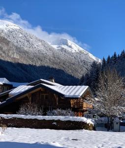 Una cabaña de troncos en la nieve con una montaña en Le Petit Chalet de Montriond, en Montriond