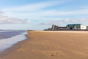 a sandy beach with buildings and the ocean at Stylish apartment with balcony, minutes from beach in Redcar