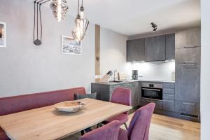 奧伯古格爾的住宿－Das Apart Rauch Gurgl，厨房以及带木桌和紫色椅子的用餐室。
