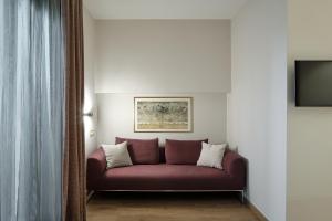 a red couch in a room with a tv at Windsor Merano Hotel & Suites in Merano