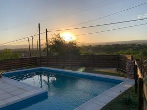 a swimming pool with the sunset in the background at CABAÑA EN TANTI in Tanti