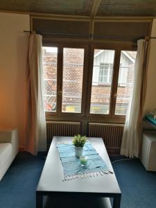 a living room with a table and two windows at Casa Koraal - Old Town Zug in Zug