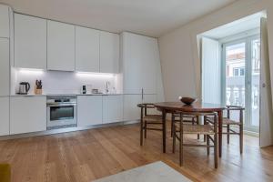 een keuken met witte kasten en een tafel en stoelen bij Stunning Apartment in Heart of Lisbon by LovelyStay in Lissabon