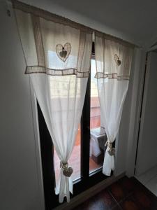 - une fenêtre avec des rideaux blancs et des cœurs dans l'établissement Dany’s house, à Monopoli