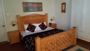a bedroom with a large wooden bed with pillows at Pine Top Hotel Murree in Murree