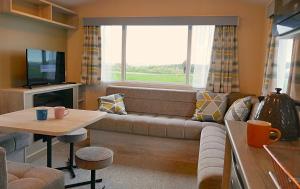 a living room with a couch and a window at Plot 8 Lakeside Cabin, Wyldecrest, Millom in Millom