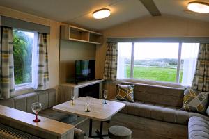 a living room with a couch and a table at Plot 8 Lakeside Cabin, Wyldecrest, Millom in Millom