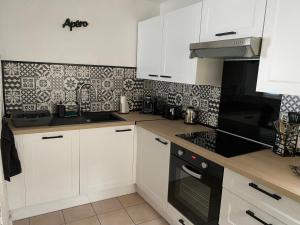 una cocina con armarios blancos y electrodomésticos negros en Le Marais Vous - Duplex en centre-ville., en Provins