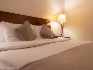 a bed with white sheets and pillows next to a lamp at Arena Space Hotel in Amman