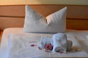 Una cama con toallas blancas y flores. en Hotel Trebeltal, en Demmin