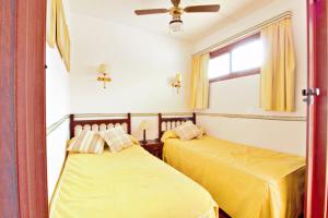 two beds in a room with yellow sheets and a window at Studio with a canarian atmosphere in the south in Costa Del Silencio