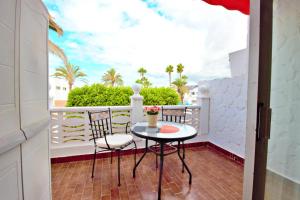 een balkon met een tafel en stoelen en palmbomen bij Studio with a canarian atmosphere in the south in Costa Del Silencio