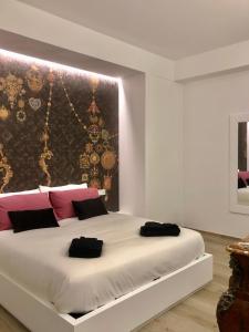 una camera da letto con un grande letto bianco con cuscini rosa e neri di Gonzaga Guest House a Napoli