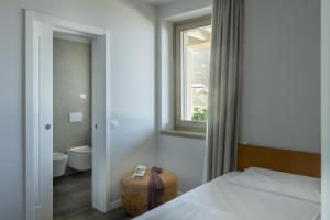 a bedroom with a bed and a window and a toilet at Relais Zenner in Toscolano Maderno