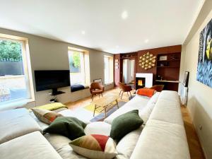 a living room with a white couch and a tv at Le Capella, magnifique maison au calme avec garage in Caen
