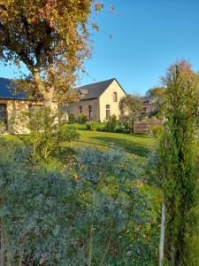 a house with a yard with trees and bushes at La Sellerie in Romagné