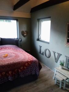 a bedroom with a red bed and two windows at Gastenverblijf 't Achterhoes in Bellingwolde