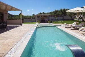 una piscina en un patio trasero con sombrilla en Koin Villa Sunrise, with Heated Pool & Whirlpool, en Perama