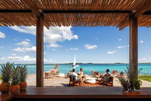 people sitting on a patio overlooking the ocean at Habitas Bacalar in Bacalar