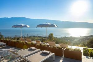 a patio with chairs and umbrellas and the ocean at Relais Zenner in Toscolano Maderno